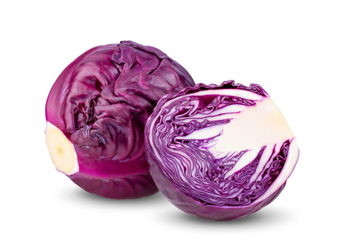 A fresh head of red cabbage on a rustic wooden surface, sliced wedges showing vibrant purple leaves